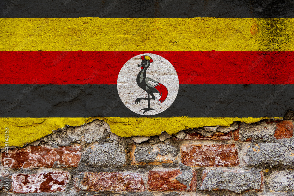 Graphic Concept with a Flag of Uganda painted on a damaged brick wall. 
