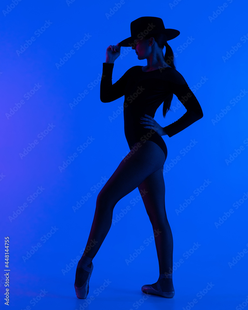Contemporary ballet dancer woman in hat posing on blue background. Professional ballerina in sexy costume of femme fatale, solo performance. Contemporary ballet dancer woman in hat posing on blue background. Professional ballerina in sexy costume of femme fatale, solo performance.