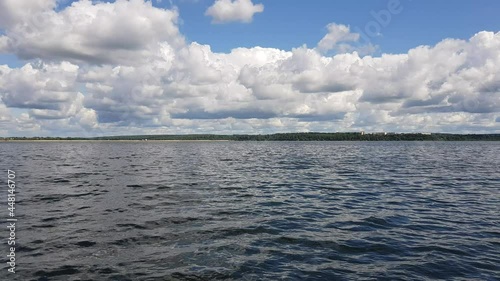 Motor boat trip along the waves of the picturesque Senezh lake. Skyline, green trees on the shore and cloudy blue sky on a sunny day. Moscow region, Russia