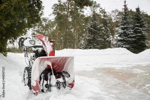A red snow-covered snow blower stands on the road after clearing the area. Clearing the area from snowfall. © goodmoments