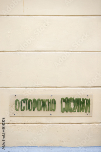 Fototapeta Naklejka Na Ścianę i Meble -  There is a warning sign in Russian on the wall of the house. The inscription on it reads: Beware of the icicles