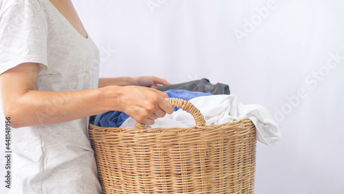 Woman holding a laundry basket full of laundry is about to wash.
