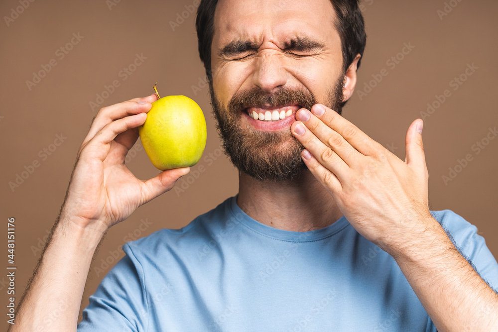 Close up portrait of nervous unhappy troubled handsome bearded man touching his cheek he has toothache isolated on beige background copyspace. Close up portrait of nervous unhappy troubled handsome bearded man touching his cheek he has toothache isolated on beige background copyspace.