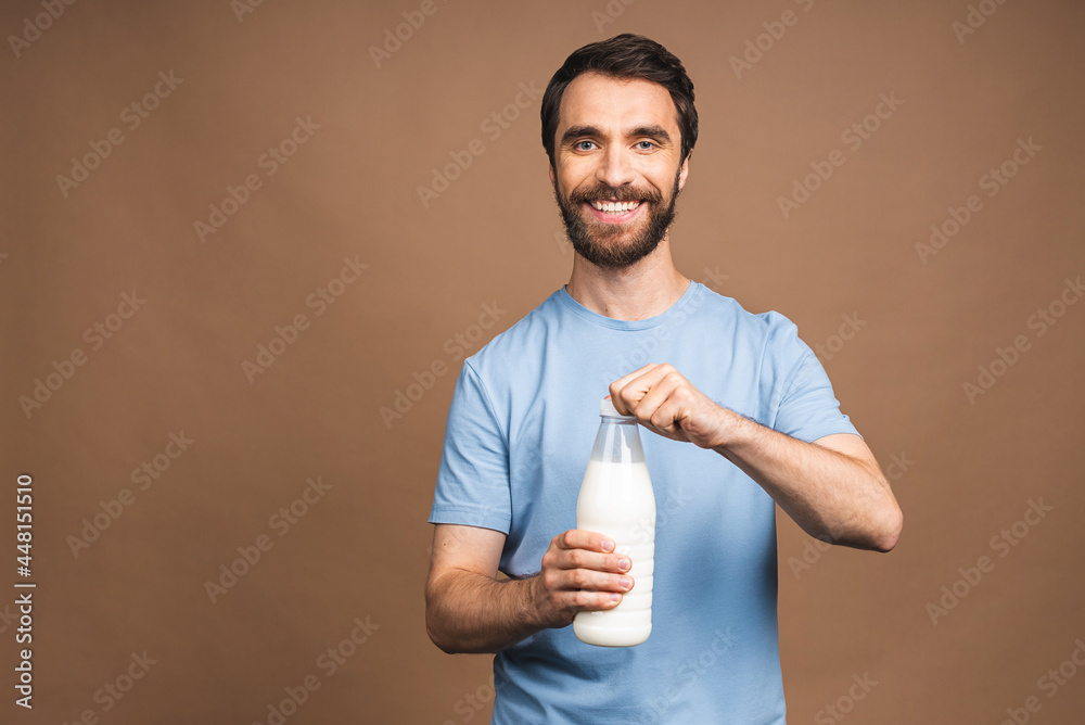 Healthy eating, diet concept! Portrait of young bearded man holding a bottle of milk isolated over beige background. Healthy eating, diet concept! Portrait of young bearded man holding a bottle of milk isolated over beige background.