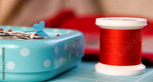 Closeup of red threads and needles in a needlecase. With selective foces on a threads. Tailoring equipment. photo