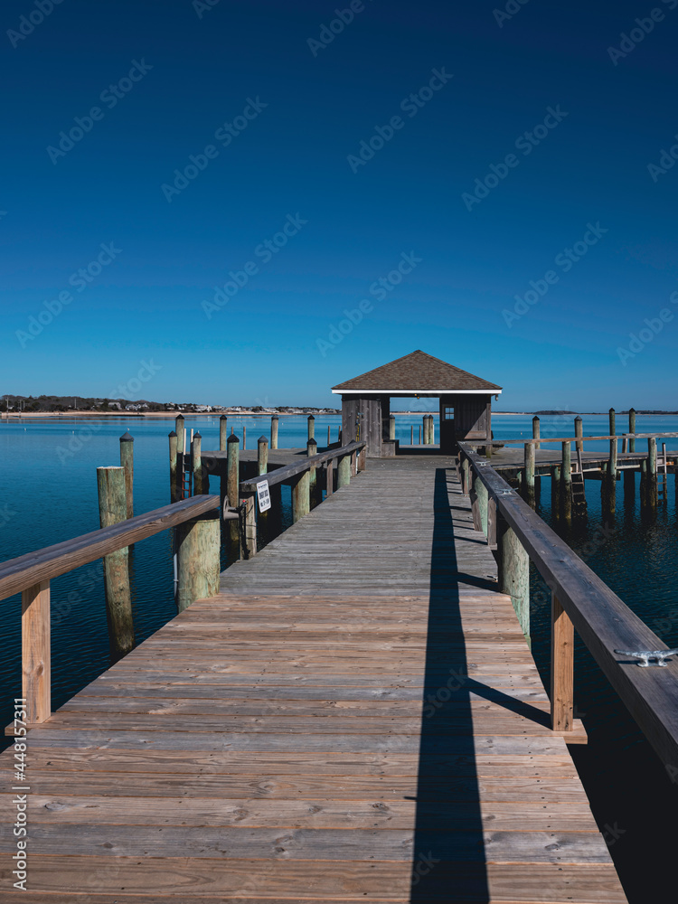 Wooden boardwalk and dock house stretching out into the sea. Seascape of Hyannis Harbor in Massachusetts.
