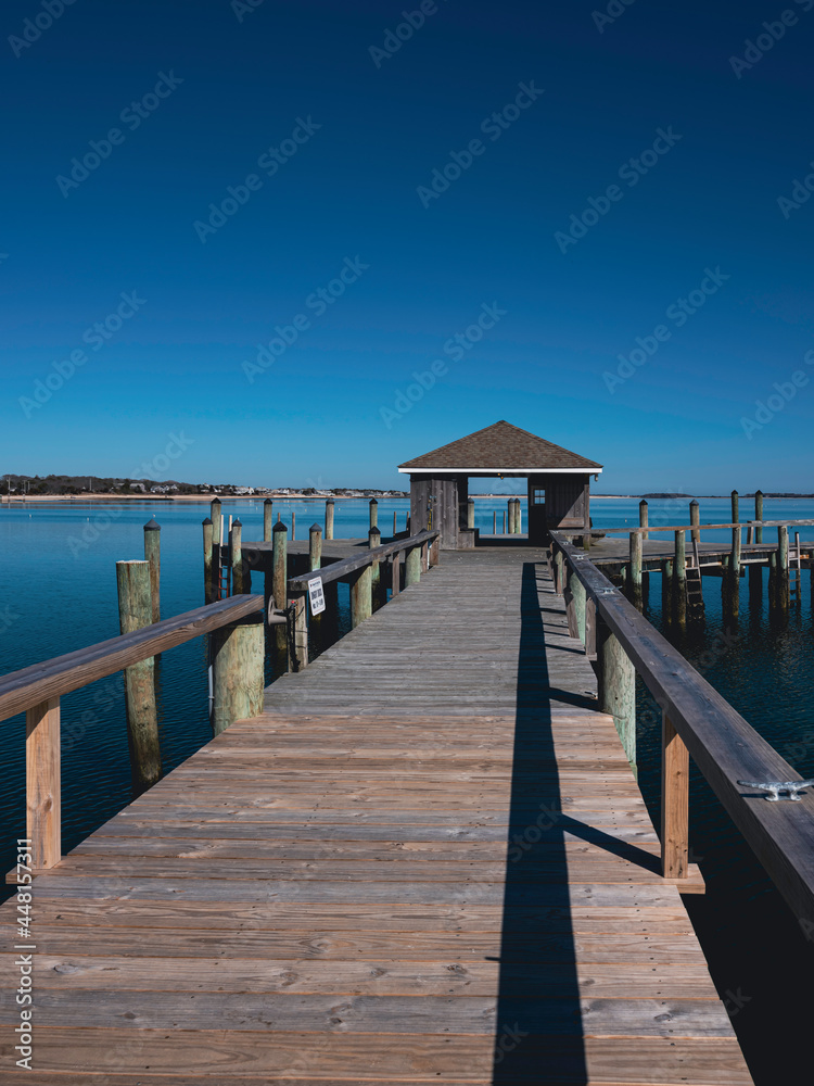 Obraz premium Wooden boardwalk and dock house stretching out into the sea. Seascape of Hyannis Harbor in Massachusetts.