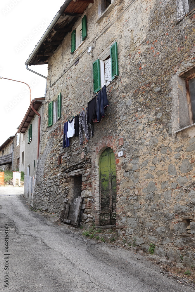 Central Italy Village Street View with Old Stone Building, Green Wooden Door and Hanging Laundry