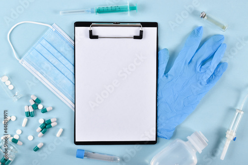 A notebook with a mask, gloves and capsules on a blue background with a place for text.