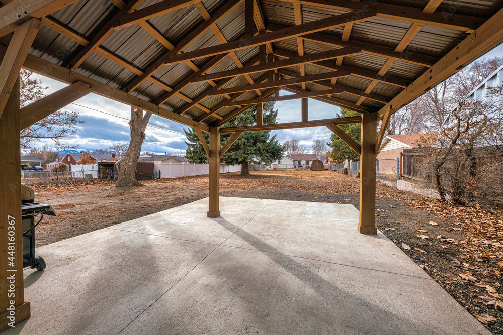 Covered patio in a large backyard with trees and fallen dry leaves Covered patio in a large backyard with trees and fallen dry leaves
