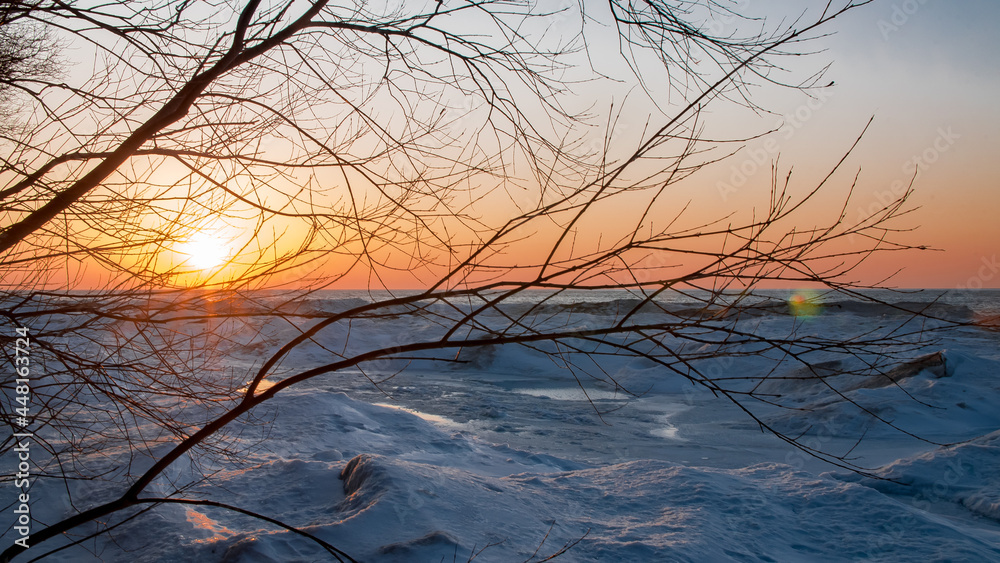 Fototapeta premium View of the sunset on a frozen lake covered by the thick ice in Ontario, Canada.