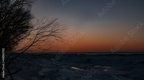 View of the sunset on a frozen lake covered by the thick ice in Ontario, Canada.