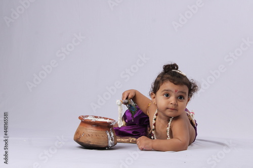 adorable Indian baby in krishna kanha or kanhaiya dress lying over white background. janmashtami concept photo