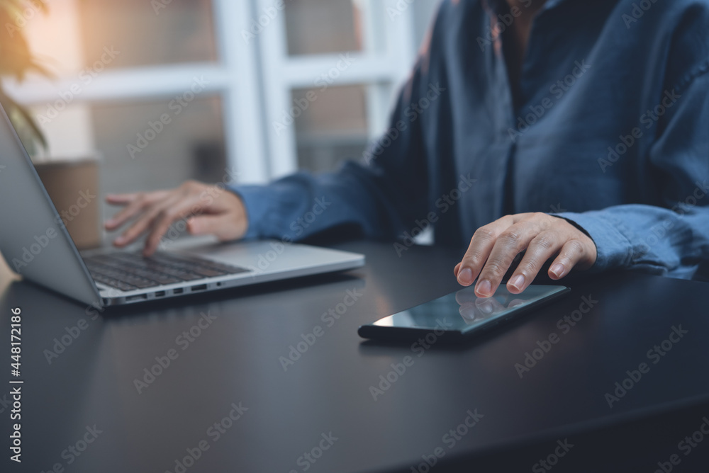 Fototapeta premium Casual businesswoman, multitasking woman, working on laptop computer and using mobile phone at home
