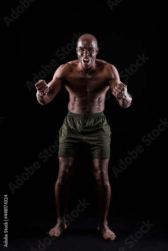 African American man facing front with fists clenched and shouting at camera