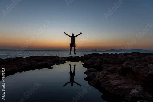 Young man jump the Sunset in Can Marroig in Formentera, Spain
