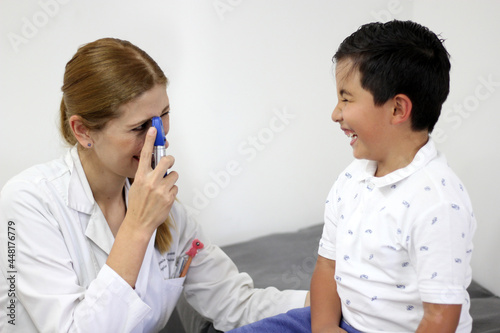Female pediatrician doctor examining a 7-year-old Latino boy in her office 