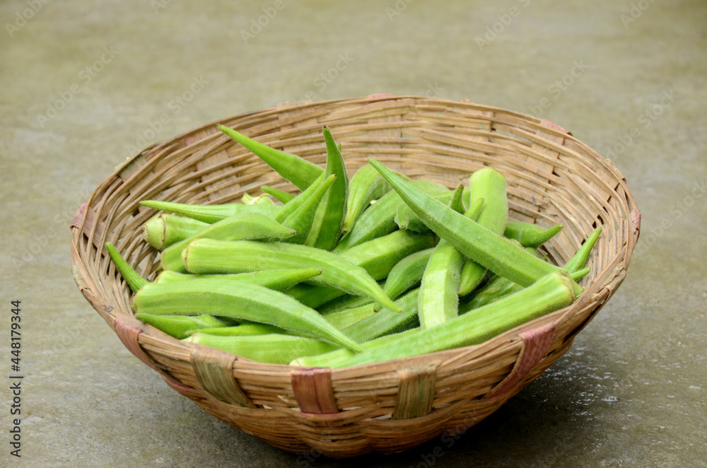 closeup the bunch ripe green ladyfinger in the basket on the brown background. closeup the bunch ripe green ladyfinger in the basket on the brown background.
