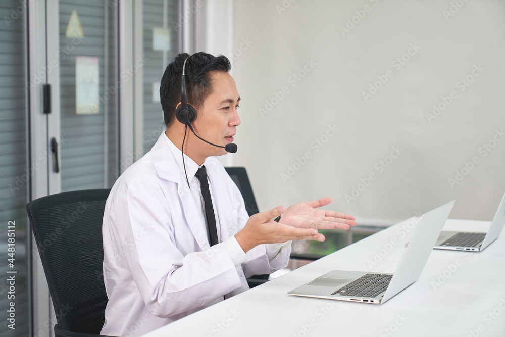 Asian male doctor waer headset and descript to patient in laptop , Online healthcare consultant service , telecommunications medical concept Asian male doctor waer headset and descript to patient in laptop , Online healthcare consultant service , telecommunications medical concept