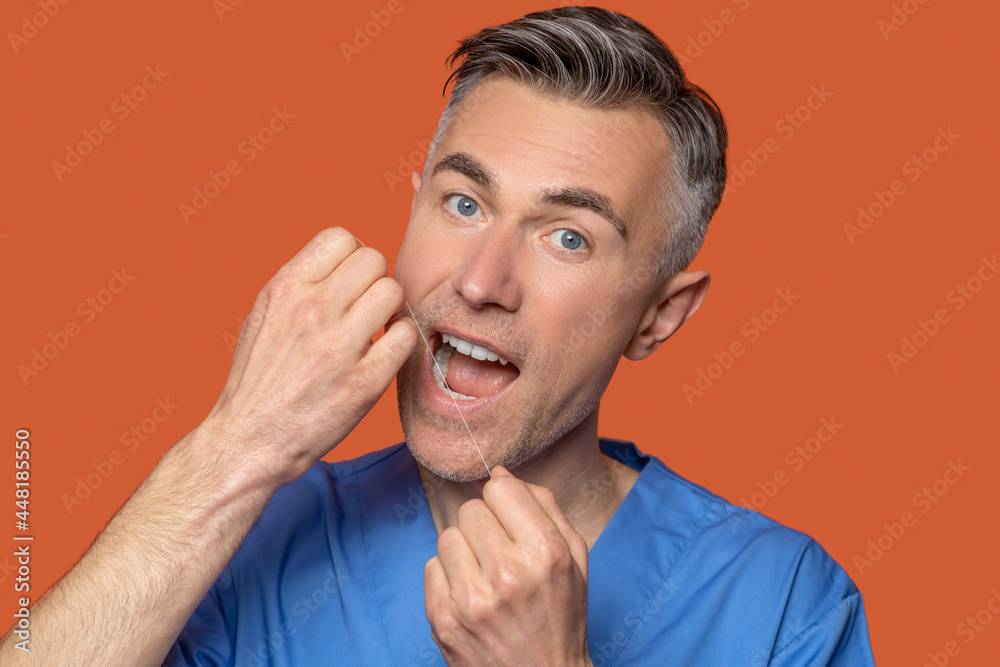 Cute gray-eyed man using dental floss Cute gray-eyed man using dental floss