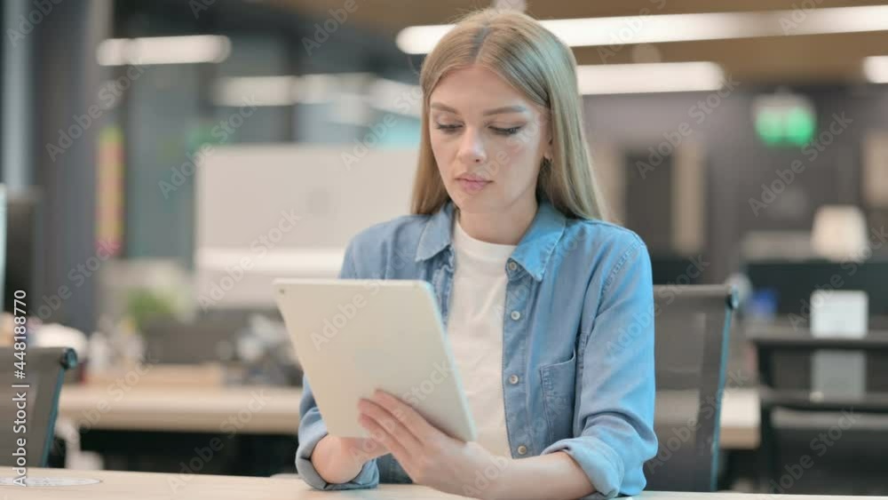 Young Woman Browsing Internet on Tablet in Office Young Woman Browsing Internet on Tablet in Office