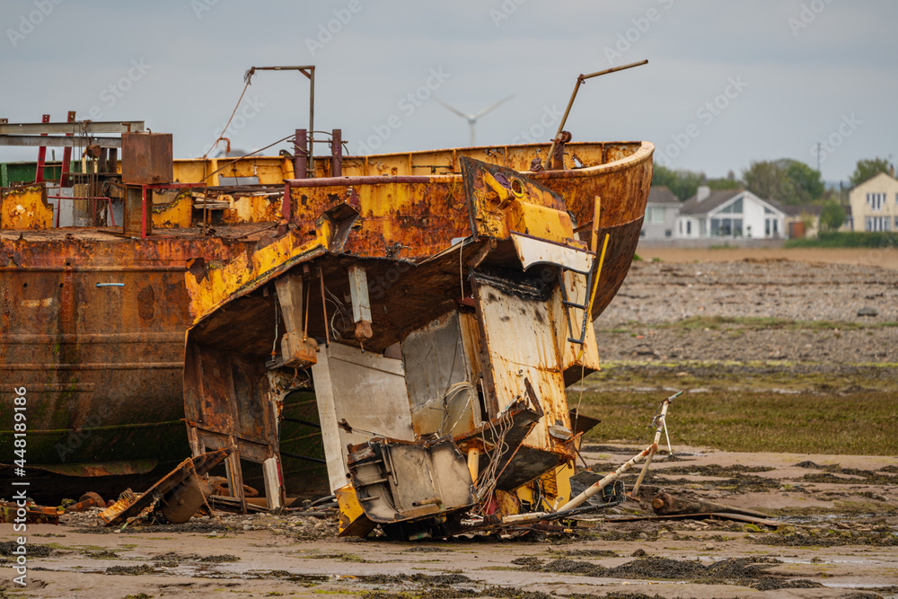 A rusty shipwreck in the mud of the Walney Channel, seen from the road to Roa Island, Cumbria, England, UK