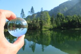 Reflektion in einer Glaskugel von einem See und Bäumen in den Bergen 