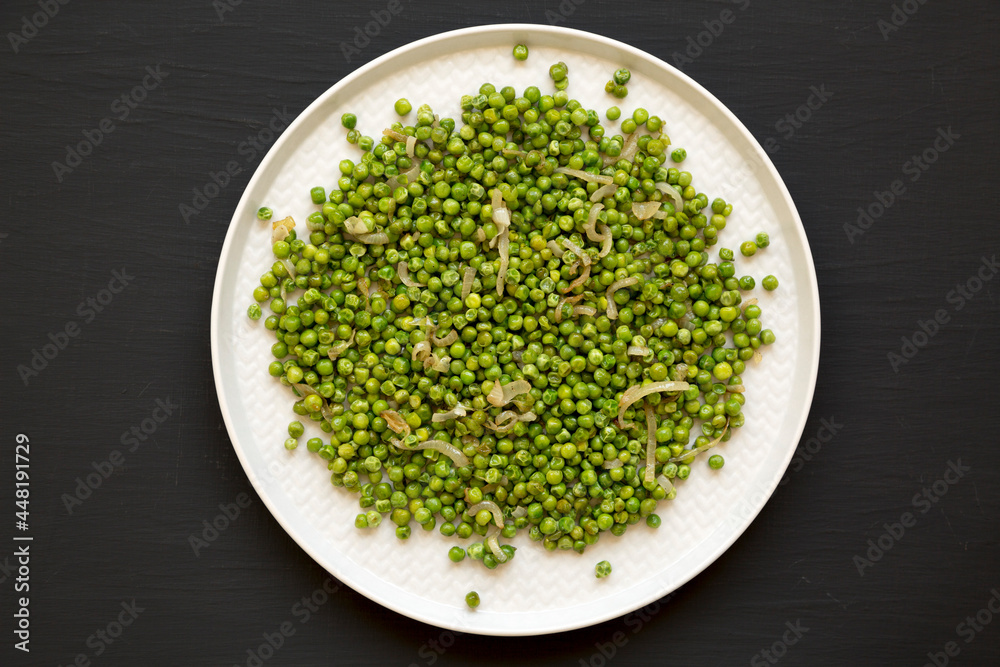 Homemade Sauteed Green Peas on a plate on a black background, top view. Flat lay, overhead, from above. Homemade Sauteed Green Peas on a plate on a black background, top view. Flat lay, overhead, from above.