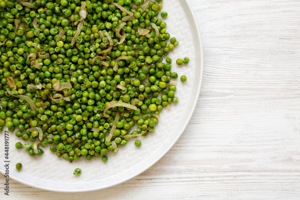 Homemade Sauteed Green Peas on a plate on a white wooden background, top view. Flat lay, overhead, from above. Homemade Sauteed Green Peas on a plate on a white wooden background, top view. Flat lay, overhead, from above.