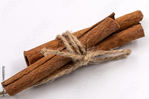Cinnamon sticks tied with rope on white background