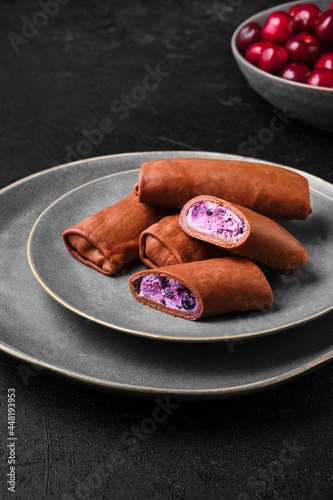 Thin chocolate pancakes stuffed with cottage cheese, blueberry and cherry