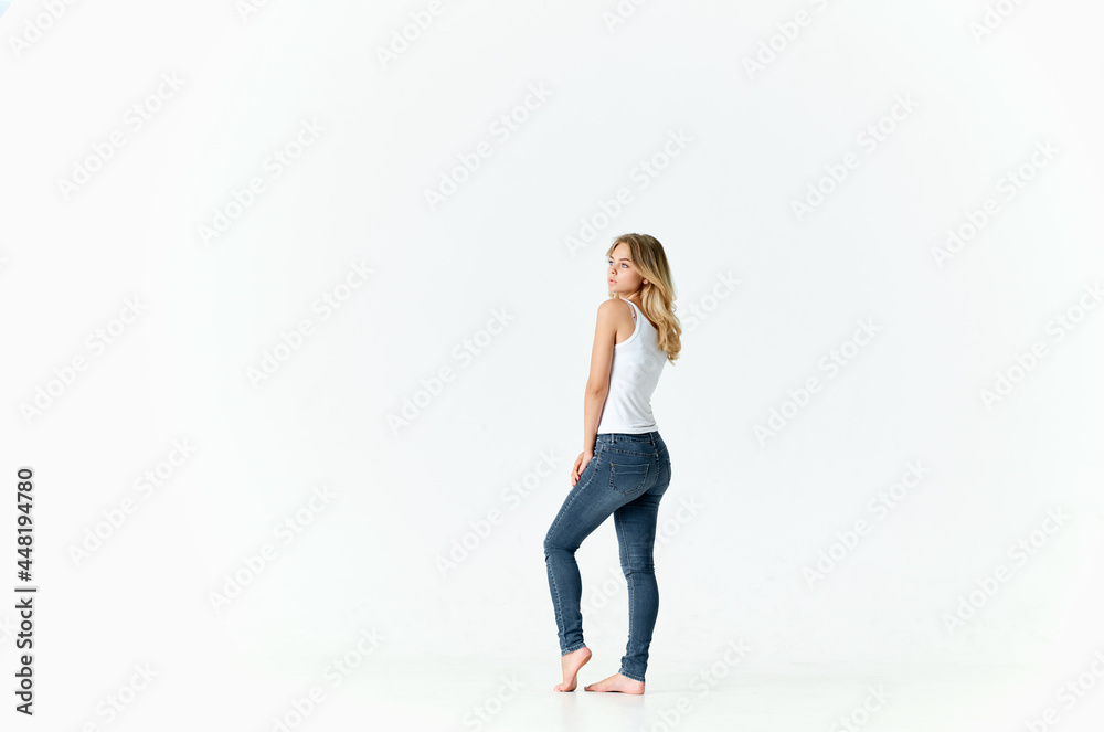 woman in jeans stands barefoot on the floor posing fashion light background woman in jeans stands barefoot on the floor posing fashion light background