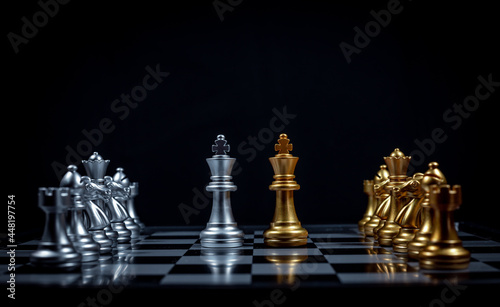 Chess board game between king silver team and golden team is stategy game as business challange competitive game ,this business stategy plan concept with black background.