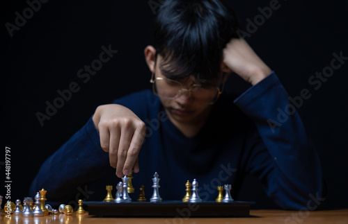 Young boy playing chess board between golden team and silver team ,he thinking serious how to winner on game is stategy and development intelligance game. photo