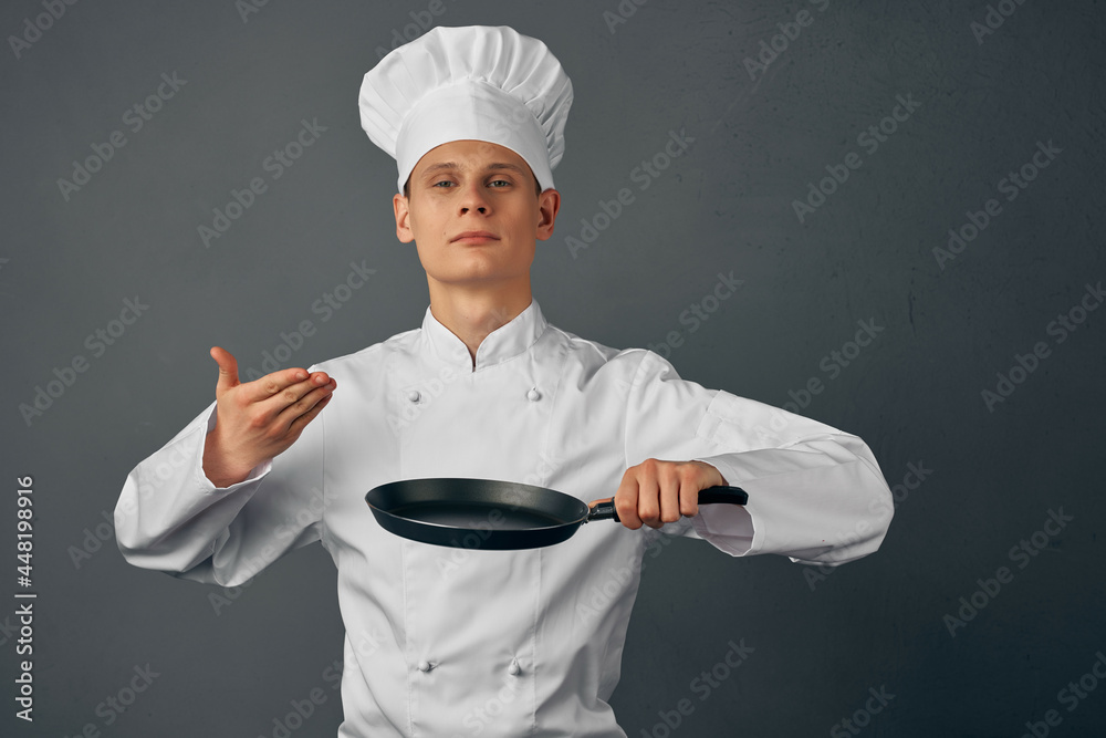 Cheerful chef in uniform frying pan in hands of restaurant cooking Cheerful chef in uniform frying pan in hands of restaurant cooking