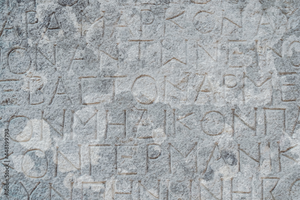 Antique greek inscriptions carved on the stone of the old ruins of an antique greek city