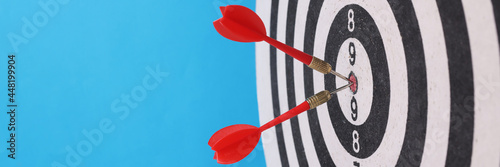 Game darts in center with darts on blue background.