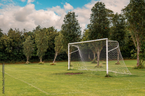 White soccer of football goal post on a grass field of a training ground.