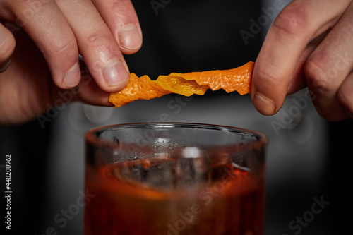 Принти на полотні bartender makes a cocktail in a glass with orange peel