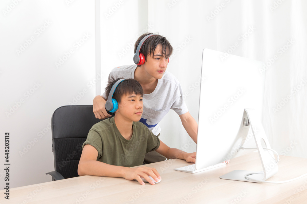 Two multiethnic teenage boys with headphone have fun with computer games at home. Two multiethnic teenage boys with headphone have fun with computer games at home.
