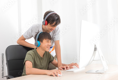 Two multiethnic teenage boys with headphone have fun with computer games at home.