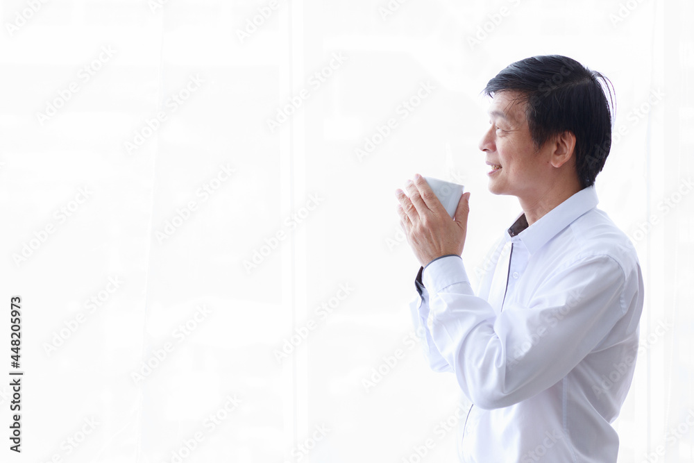 Asian old middle aged confident happy black and gray hair male businessman wears white long sleeve shirt black pants and eyeglasses in pocket stand smiling drink hot coffee from white ceramic mug Asian old middle aged confident happy black and gray hair male businessman wears white long sleeve shirt black pants and eyeglasses in pocket stand smiling drink hot coffee from white ceramic mug