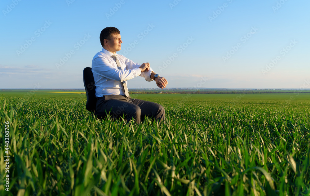 businessman sits in an office chair in a field and rests, freelance and business concept, green grass and blue sky as background businessman sits in an office chair in a field and rests, freelance and business concept, green grass and blue sky as background