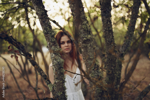 pretty woman in white dress near trees fallen leaves in the forest