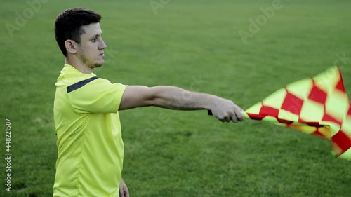 Assistant referee moving along the sideline during a soccer match. Linesman hand with flag signalling for offside trap to referee during football match