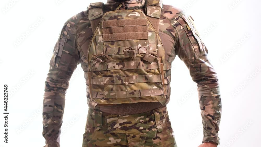 Man in combat camouflage in a bulletproof vest is wearing a war belt against a white background. Isolated Man in combat camouflage in a bulletproof vest is wearing a war belt against a white background. Isolated