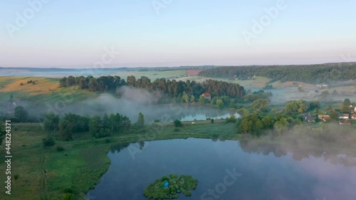 Road between two lakes in morning fog
