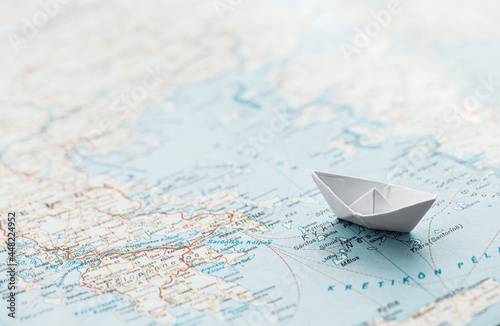 Travel concept - white paper boat on a map