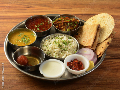 Maharashtraian Veg Thali from an indian cuisine, food platter consists variety of veggies, lentils, jeera rice, roti, sweet dish, curd, pickle etc., selective focus photo