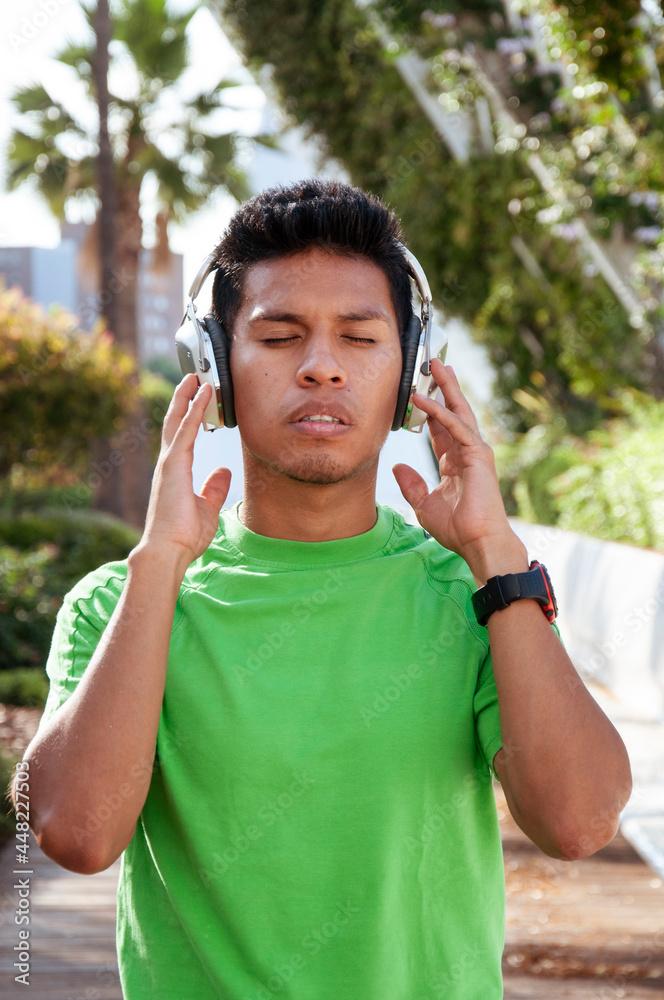 Young Latin American teenager with his eyes closed in concentration listening to the music on his headphones. Young Latin American teenager with his eyes closed in concentration listening to the music on his headphones.